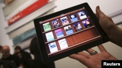 A woman holds up an iPad with the iTunes U app after a news conference introducing a digital textbook service, in New York, January 2012. (file photo)