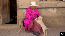 Julia Flores Colque, 117 years old, plays with Chiquita, one of the family's dogs, while sitting outside her home in Sacaba, Bolivia, Aug. 23, 2018.