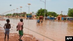 Des enfants marchent dans une rue inondée de Niamey le 15 juin 2017.