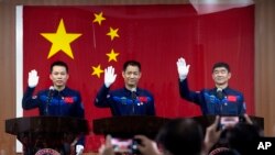 Astronot China, dari kiri: Tang Hongbo, Nie Haisheng, dan Liu Boming melambaikan tangan mereka pada konferensi pers di Pusat Peluncuran Satelit Jiuquan menjelang peluncuran Shenzhou-12 dari Jiuquan, barat laut China, Rabu, 16 Juni 2021. (AP Photo/Ng Han Guan)