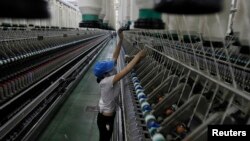 FILE- A woman works at a yarn-weaving plant of the Ha Nam textile company in Phu Ly city, about 60 km (37 miles) south of Hanoi, July 4, 2013. 