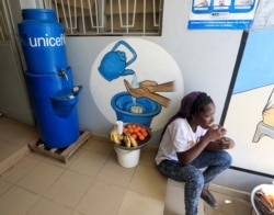 Seorang anak perempuan duduk dekat tempat mencuci tangan di pintu masuk pusat kesehatan di Pikine, di pinggiran Dakar, Senegal, 9 Maret 2020. (Foto: Reuters)