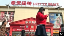 一名女子走在中國北京樂天超市前(2017年3月17日)
