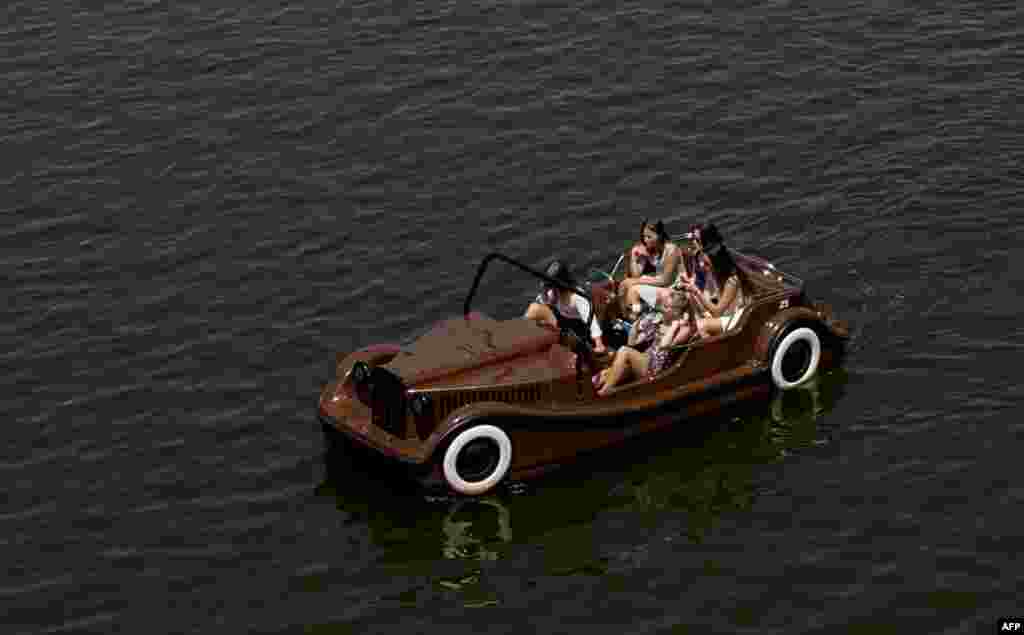 Tourists enjoy a sunny day as they cruise Vltava river in a pedal boat near the famous Charles bridge in Prague, Czech Republic.