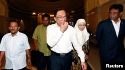 FILE - Malaysian opposition leader Anwar Ibrahim (C) and his wife Wan Azizah arrive at a court house in Putrajaya, March 7, 2014. 