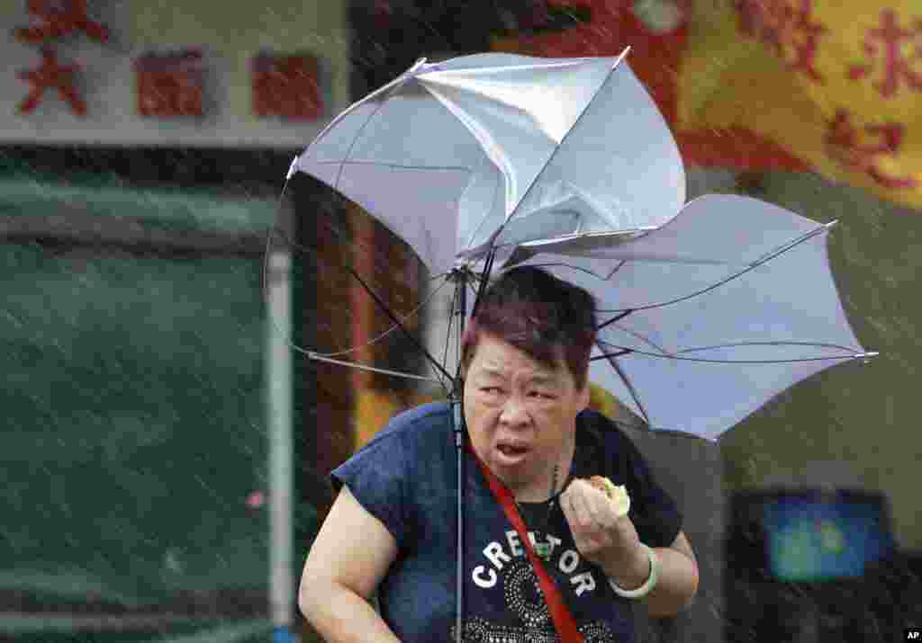 Seorang perempuan kesulitan memegang payungnya yang tertiup angin di tengah Topan Megi yang melanda Taipei. (AP/Chiang Ying-ying)