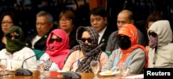 Family members of alleged drug pushers who were killed during a meth raid wear masks during a Senate hearing regarding a crackdown on illegal drugs in Pasay, Metro Manila, Philippines, Aug. 23, 2016.