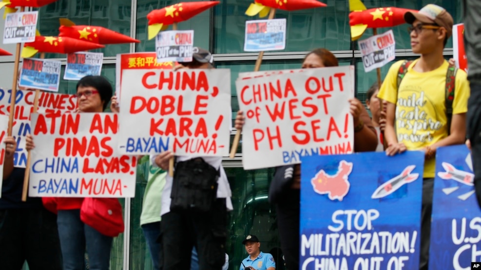 Police guard the entrance to the Chinese Consulate as environmental activists protest the alleged military build-up by China on the disputed group of islands at the South China Sea, Jan. 24, 2017 in the financial district of Makati east of Manila.