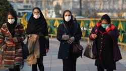 Para pejalan kaki mengenakan masker di Teheran di tengah perebakan virus corona di sana.