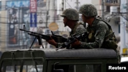 Members of the Philippine Marines hold their weapons aboard a truck as they block a road during fighting between government soldiers and Muslim rebels of Moro National Liberation Front (MNLF) in Zamboanga city in southern Philippines, Sept. 15, 2013.