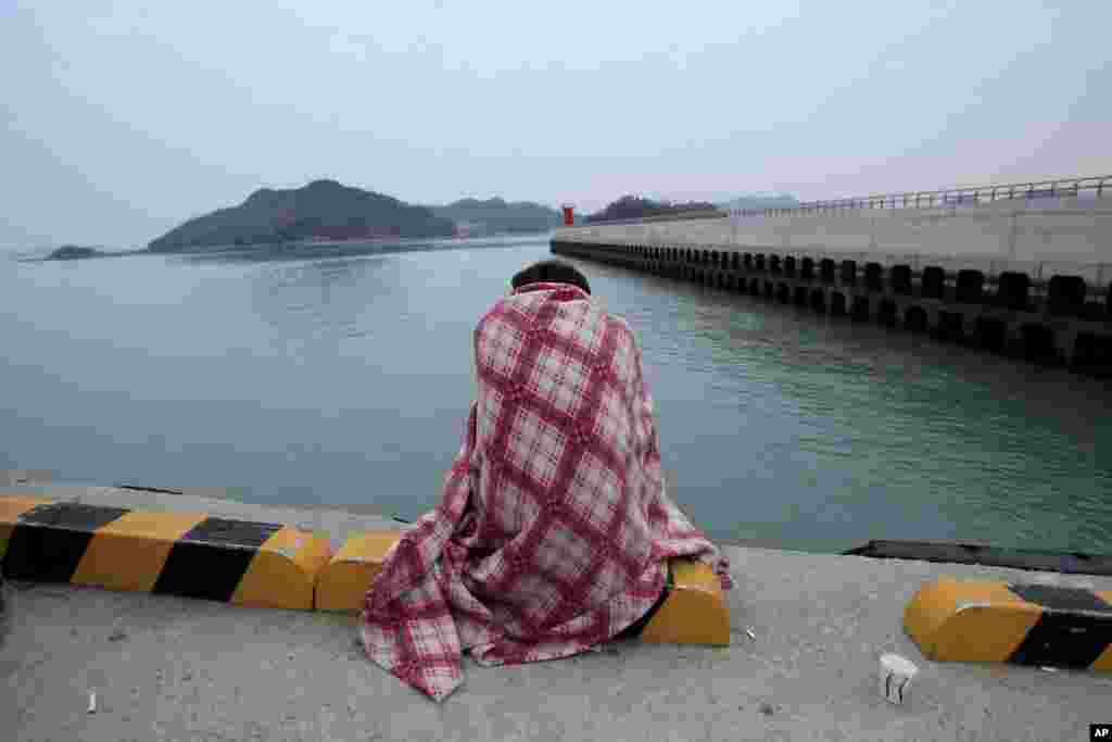 한국 진도 항구에서 실종된 희생자들의 유가족이 추위에 떨며 소식이 오기를 기다리고 있다.