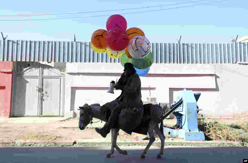 مرد افغان بادکنک فروش که سوار بر الاغ است.
