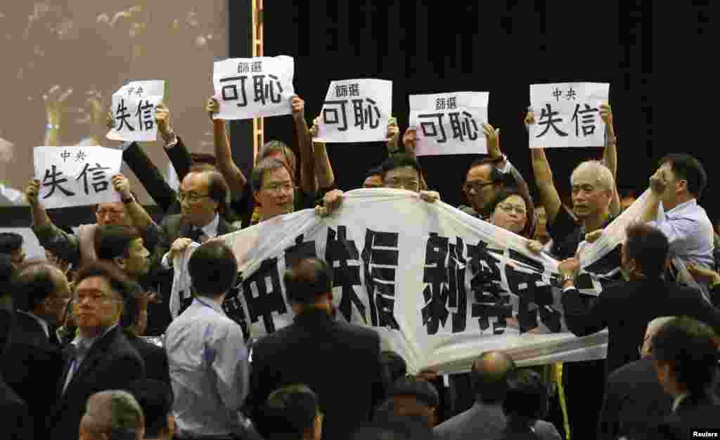 Para pembuat undang-undang pro-demokrasi memegang spanduk dan plakat sebagai protes saat Li Fei berbicara dalam sebuah sesi di Hong Kong (1/9). (Reuters/Bobby Yip)