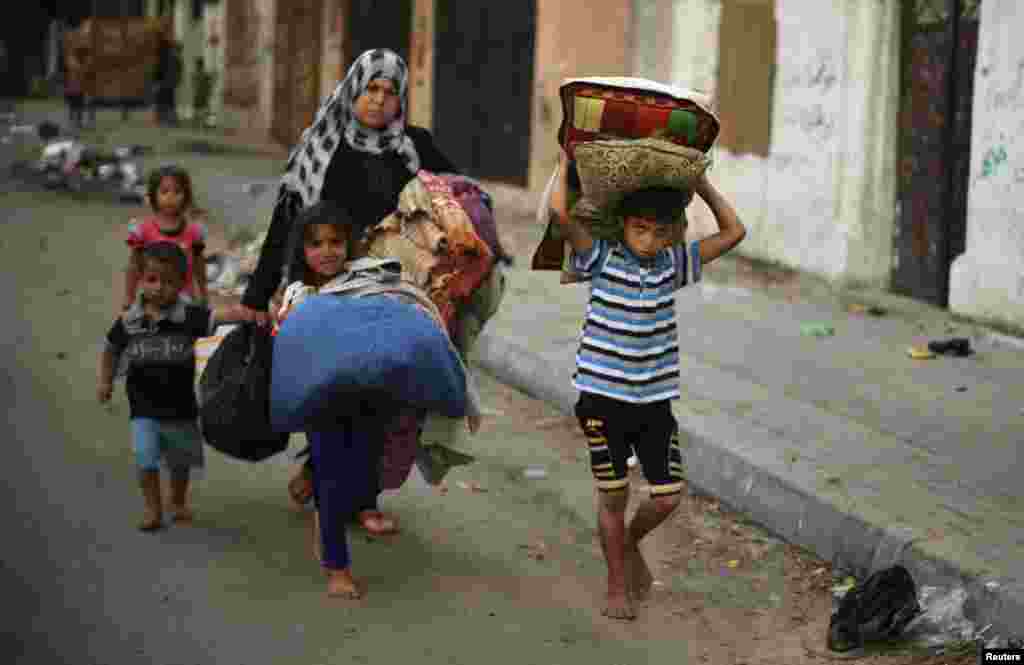 Palestinians carry their belongings as they flee Israeli airstrikes, in Gaza City, July 29, 2014.