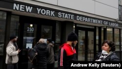 Les gens se rassemblent à l'entrée des bureaux du département du Travail de l'État de New York, qui ont fermé au public en raison de l'épidémie de maladie à coronavirus (COVID-19) dans l'arrondissement de Brooklyn à New York, États-Unis, le 20 mars 2020.