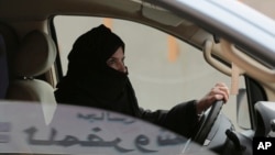 FILE - Aziza Yousef drives a car on a highway in Riyadh, Saudi Arabia, March 29, 2014, as part of a campaign to defy Saudi Arabia's ban on women driving. Carmakers hoping to sell more cars in Saudi Arabia are applauding the king's order to draw up new rules allowing women to drive.