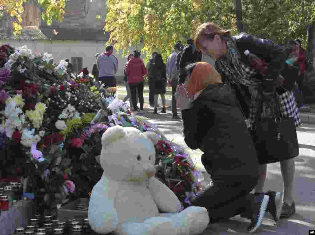 A woman prays near a memorial to people killed during a shooting rampage at a vocational college in Kerch, Crimea.