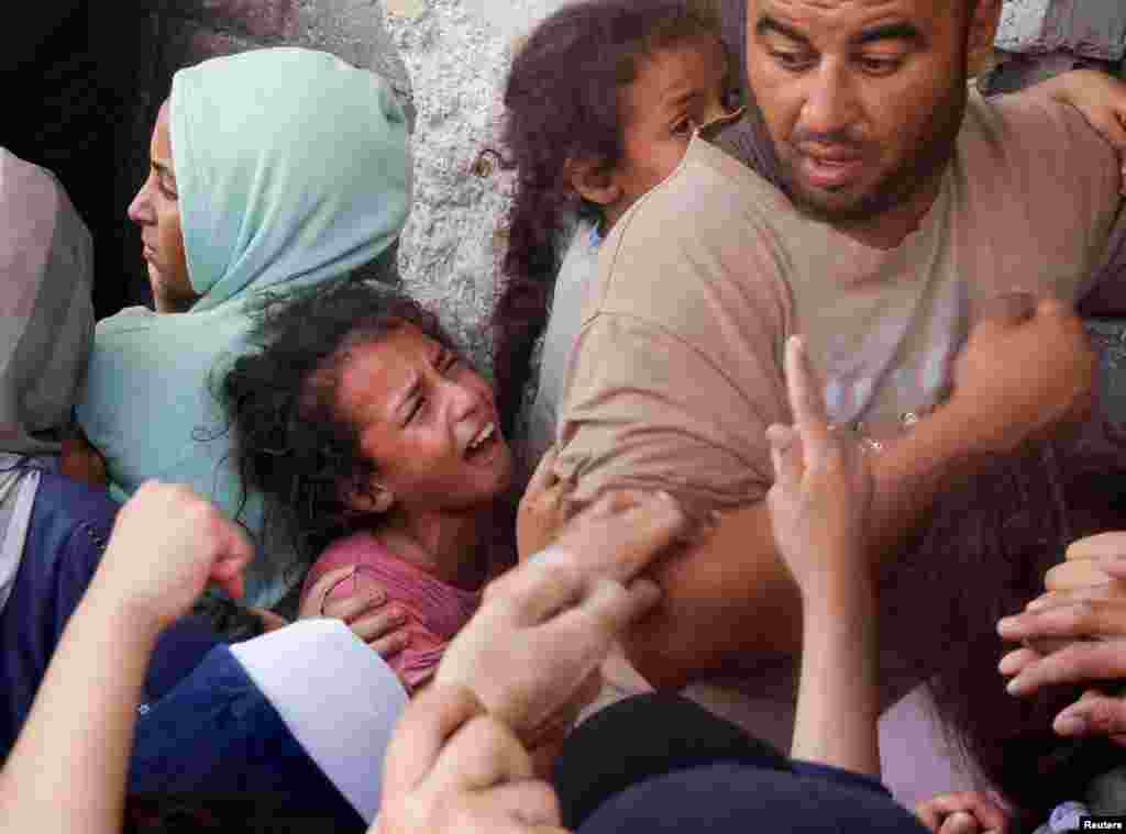 A girl reacts as Palestinians gather to buy bread from a bakery in Khan Younis, southern Gaza Strip, amid the Israel-Hamas conflict.