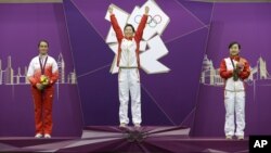 China's Yi Siling, center, celebrates winning the gold medal in the women's 10-meter air rifle event, alongside silver medalist Poland's Sylwia Bogacka, left, and bronze medalist China's Yu Dan, right, at the 2012 Summer Olympics in London, Saturday, July