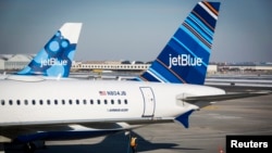 FILE - An airport worker fuels a JetBlue plane on the tarmac of the John F. Kennedy International Airport.