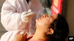 A health worker takes a nasal swab sample to test for COVID-19 outside a railway station in Ahmedabad, India, Dec. 19, 2020. 