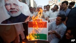 Pakistanis burn a representation of an Indian flag and a poster of Indian Prime Minster Narendra Modi during a protest to express support and solidarity with Indian Kashmiri people