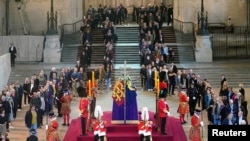 FILE: Members of the public file past the coffin of Queen Elizabeth II, draped in the Royal Standard with the Imperial State Crown and the Sovereign's orb and sceptre, lying in state on the catafalque in Westminster Hall, at the Palace of Westminster, London, ahead of her funeral on Monday. Picture date: Thursday September 15, 2022.