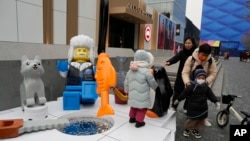 Children play near a display depicting an elderly person at a shopping mall in Beijing, Wednesday, Jan. 17, 2024. China's population dropped by 2 million people in 2023, the government recently. (AP Photo/Ng Han Guan). (AP Photo/Ng Han Guan)