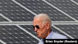 Joe Biden, yang saat itu masih kandidat presiden, berjalan melintas panel surya saat mengunjungi Insitiatif Energi Terbarukan Kawasan Plymouth, di New Hampshire, pada 4 Juni 2019. (Foto: Reuters/Brian Snyder)