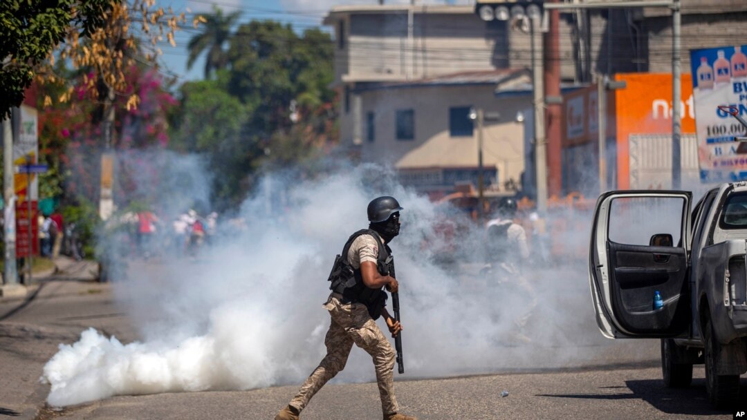A police officer runs away from tear gas during a protest to demand the resignation of Haiti's President Jovenel Moise in Port-au-Prince, Haiti, Feb. 10, 2021. 