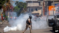 A police officer runs away from tear gas during a protest to demand the resignation of Haiti's President Jovenel Moise in Port-au-Prince, Haiti, Feb. 10, 2021. 