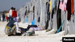 A Kurdish refugee woman from the Syrian town of Kobani washes dishes at a refugee camp in the border town of Suruc, Sanliurfa province, Turkey, Nov. 11, 2014. 