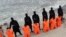 FILE - Captives in orange jumpsuits — purported to be Egyptian Christians —kneel in front of armed Islamic State militants along a beach said to be near Tripoli, in this still image from an undated video made available on social media, Feb. 15, 2015.