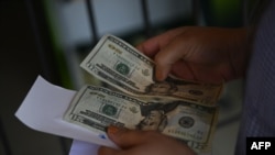 Una mujer cuenta dinero fuera de una agencia de cobro de remesas de Estados Unidos en San Isidro, 70 km al noreste de San Salvador, el 10 de junio de 2020. 