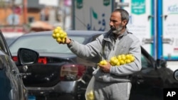 An Egyptian vendor sells lemons at a traffic light in Cairo, Egypt, Wednesday, Feb. 22, 2023. 