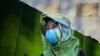 A woman wearing a face mask and a face shield walks on a street in Beijing, China.