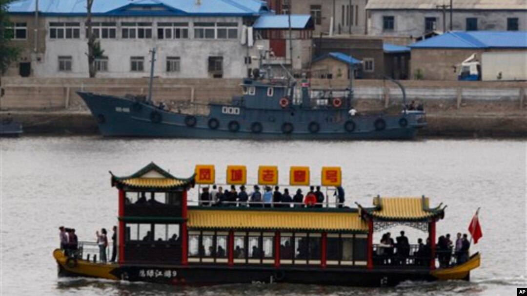 Sebuah perahu wisata China melewati kapal patroli Korea Utara yang sedang berlabuh di tepi sungai Sinuju, Korea Utara, terlihat dari kota perbatasan Dandong di propinsi Liaoning, China (Foto: dok). 