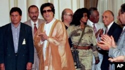 Libyan leader Muammar Gaddafi (C) arrives at Cairo university for a meeting with university professors, The armed woman to the right of Gaddafi is his personal bodyguard, May 27, 1996.