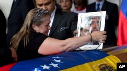 Luz Alban, the sister of opposition activist Fernando Alban, places a framed portrait of her brother shadowed by an image of Jesus Christ over the flag-draped casket containing his remains, during a ceremony at the National Assembly headquarters, in Caracas, Venezuela, Oct. 9, 2018.