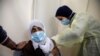 FILE - A Palestinian health worker gives a woman a dose of AstraZeneca vaccine against the coronavirus disease (COVID-19) during a vaccination drive in Tubas, in the Israeli-occupied West Bank.