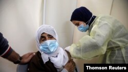 FILE - A Palestinian health worker gives a woman a dose of AstraZeneca vaccine against the coronavirus disease (COVID-19) during a vaccination drive in Tubas, in the Israeli-occupied West Bank.