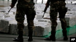 FILE - Police officers stand guard over seized cocaine they present to the press in Lima, Peru, Sept. 1, 2014. 