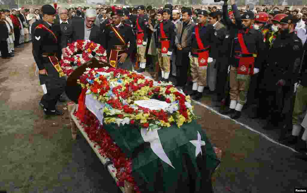 President of the Awami National Party Asfandyar Wali Khan (C) lays a wreath at the coffin of the provincial minister for local government Bashir Ahmad Bilour, who died of his wounds from a bombing attack, during his funeral at the Army Stadium in Peshawar