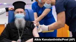 Tokoh agama Kristen Ortodoks Yunani, Metropolitan Hierotheos of Nafpaktos da Agios Vlasios, menerima suntikan dosis pertama vaksin COVID-19 di Rumah Sakit Evangelismos, di Athena, Minggu, 27 Desember 2020. (Alkis Konstantinidis/Pool via AP)