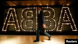 Seorang pria berjalan melewati logo kelompok pop Swedia terkenal ABBA di "ABBA — The Museum" di Stockholm, 6 Mei 2013. (Foto: dok.)