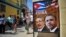 Tourists walk next to a poster of Cuban President Raul Castro and US president Barack Obama in Havana, on March 18, 2016. 
