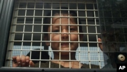 FILE - Ethnic Uighur Muslim boy stands inside a police van in Khlong Hoi Khong of southern Songkhla province, Thailand. He was in a group of 200 people rescued from a human trafficking camp.