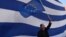 A man waves an European flag in front of giant Greek one, during a pro-European demonstration in front of the Greek parliament in Athens on June 22, 2015. 