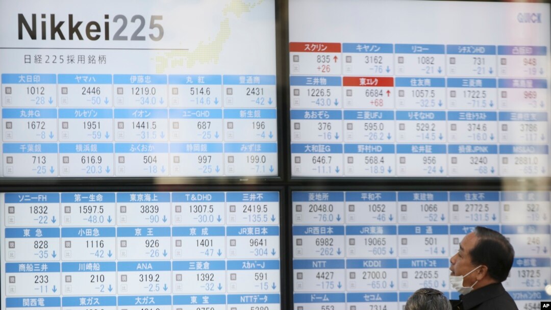 Dua orang warga tengah mengamati papan elektronik di sebuah perusahaan sekuritas Tokyo (21/9).