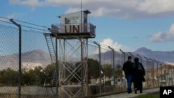 A couple walks past a U.N. guard post at the fence that divides the Greek and Turkish Cypriots areas, as they stroll at the Turkish Cypriot northern part of the divided capital Nicosia in the eastern Mediterranean island of Cyprus, Jan. 11, 2017.